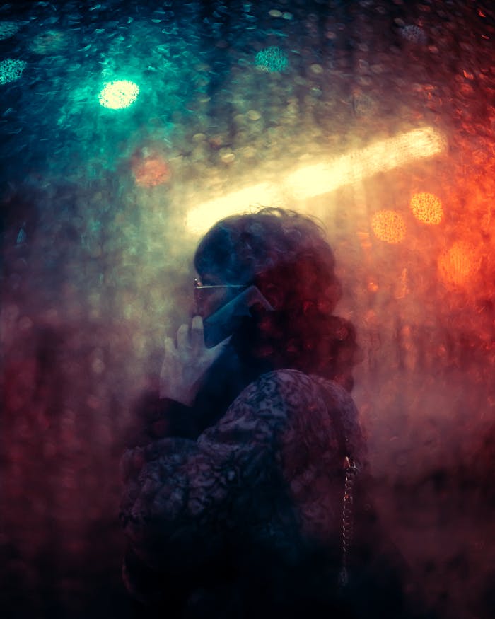 services-07 Artistic street photography of a woman talking on the phone behind a rainy window at night in Warsaw.