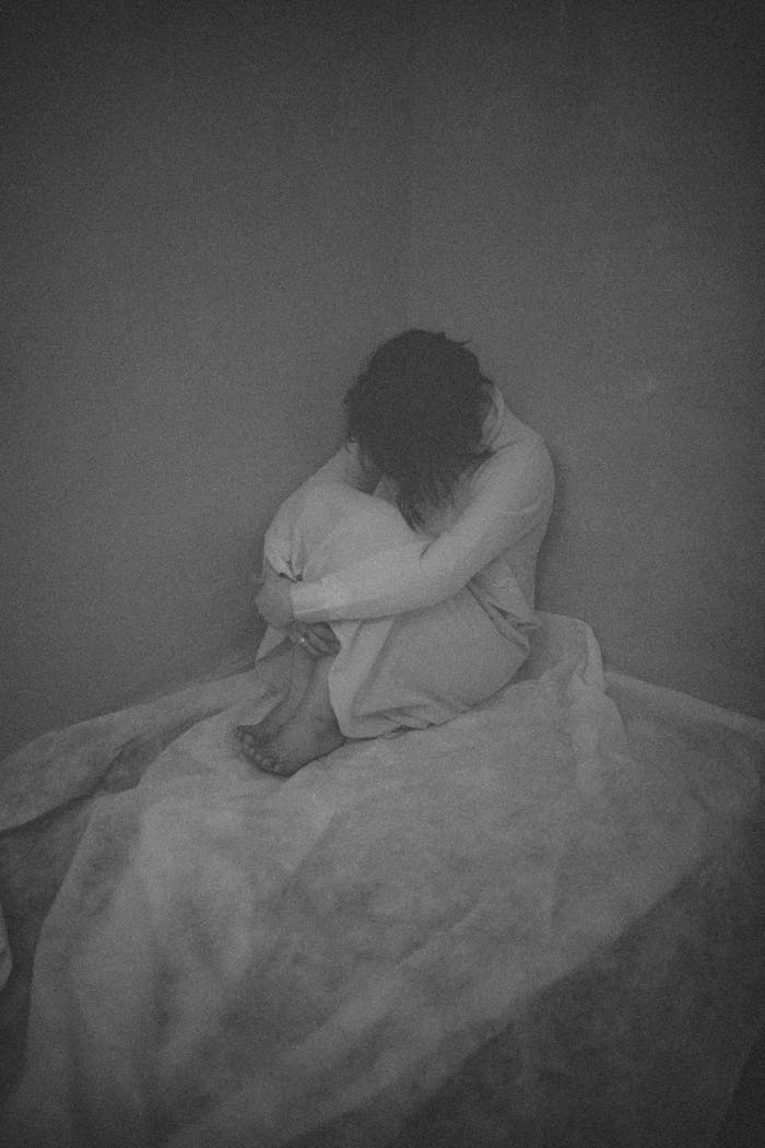 portfolio-04 A black and white image capturing a woman sitting alone, conveying deep emotions.