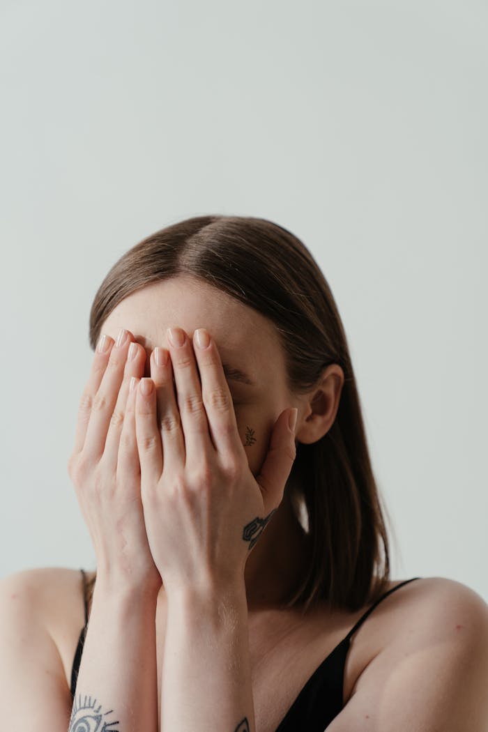 portfolio-08 A woman covers her face with hands, exuding a sense of shyness and anonymity.