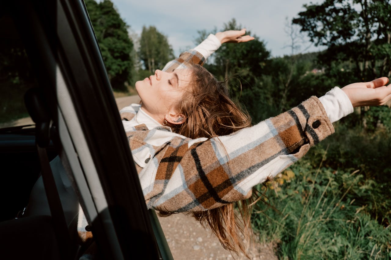 Woman enjoying a carefree ride through a lush forest, arms outstretched in the breeze.